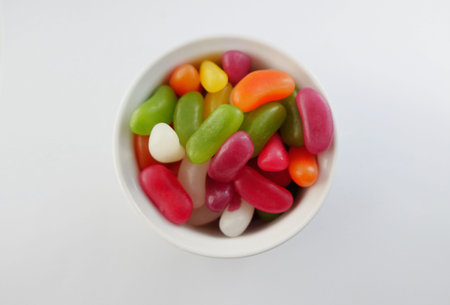 Small pot of assorted coloured jelly beans on white background with copy space