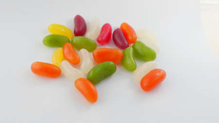 Assorted brightly coloured jelly beans lying on plain white surfaceの写真素材