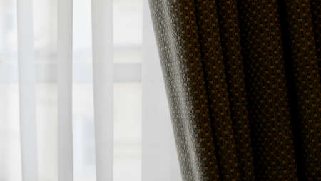 Voile curtain in front of window with textured pleated fabric to sideの写真素材