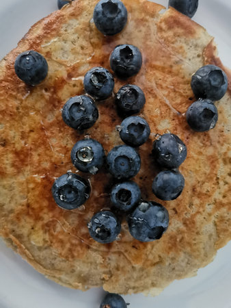 Top view of oatmeal pancake with blueberries and drizzled with honeyの写真素材