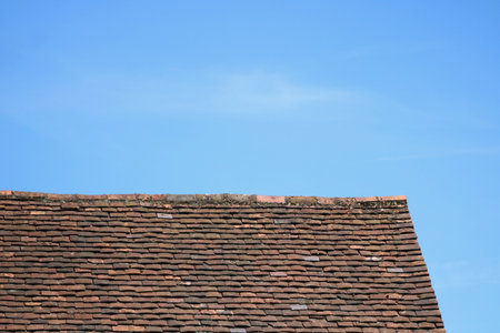 Deep blue sky above old rustic tiled roof with copy spaceの写真素材