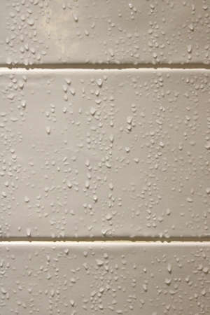 Vertical image of water droplets running down beige bathroom tilesの写真素材