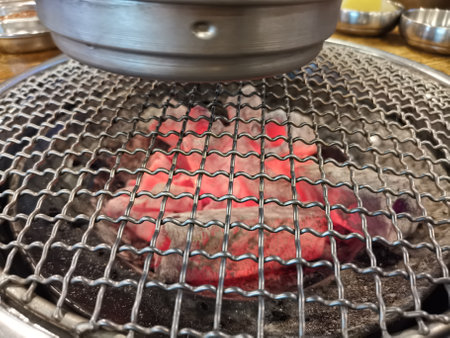 Metal Korean barbecue with red hot coals and chimney aboveの写真素材