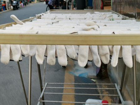 White fabric gloves hanging from drying rack in the street