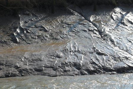 Full frame image of mud flat with small river in foreground