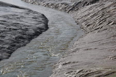 Full frame image of mud flat with small river running through
