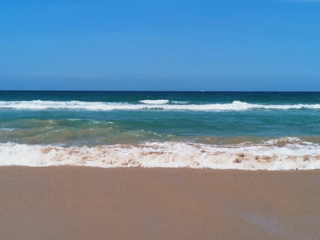 Beautiful beach scene with sand in foreground and rolling waves in backgroundの写真素材