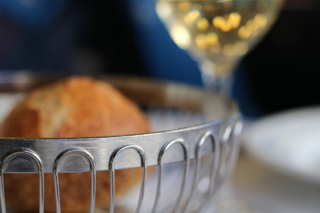 Bread roll in metal bread basket with wine in backgroundの写真素材