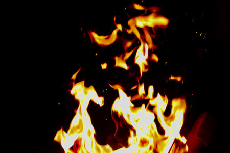 Bright golden orange flames against black background with copy space