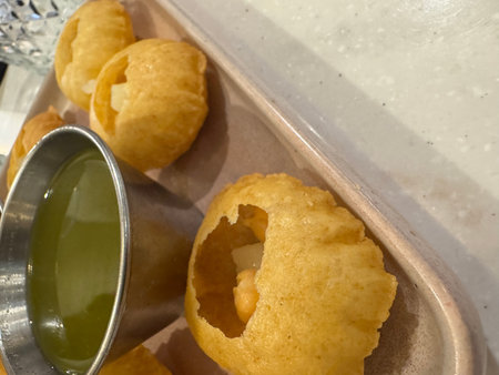 Freshly cooked panipuris with chickpea filling and sauce on tray