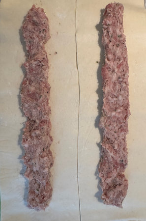 Raw sausage meat on pastry ready to be made into sausage rollsの写真素材