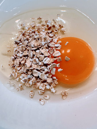 Raw egg in white dish with uncooked oats