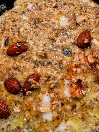 Close up of omelette mixture in small frying pan with oats, nuts, seeds, cinnamonの写真素材
