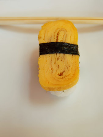 Sushi with a Japanese omelet on top and chopsticks in the background.の写真素材