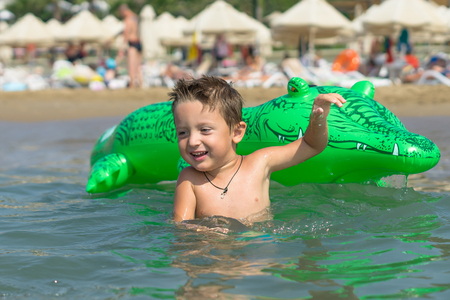 Portrait of a smiling little baby boy playing in the sea, ocean. Positive human emotions, feelings, joy. Funny cute child making vacations and enjoying summer.の写真素材