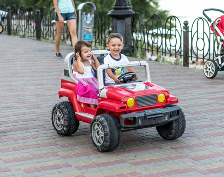 Smiling little brother and sister driving by toy car