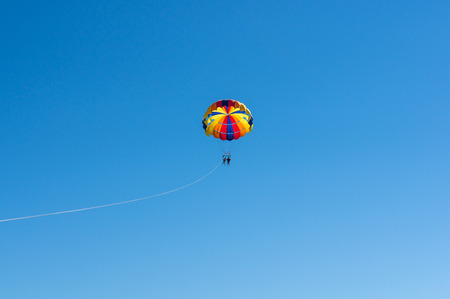 Happy couple Parasailing in Dominicana beach in summer. Couple under parachute hanging mid air. Having fun. Tropical Paradise. Positive human emotions, feelings, family, children, travel, vacation. Spring and summer holidays.の写真素材