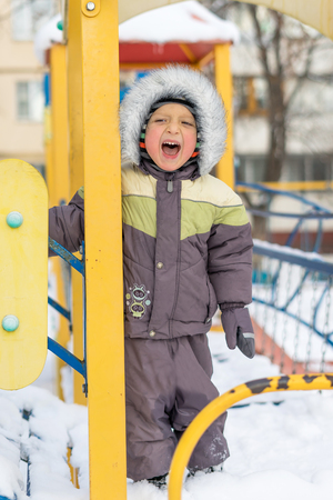 Portrait of a happy little boy playing with a snow outdoor. Winter day. Happy family. Positive human emotions, feelings, joy. Active winter game.の写真素材