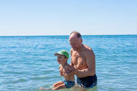 Smiling grandfather and grandson playing at the seaの写真素材