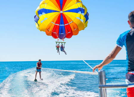 Happy couple Parasailing in Dominicana beach in summer. Couple under parachute hanging mid air. Positive human emotions, feelings, family. Young man glides on water skiing on the waves.Healthy lifestyle.の写真素材