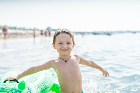 Portrait smiling little baby boy playing in the sea, ocean. Happy family having fun on tropical white beach.  Positive human emotions, feelings, joy. Funny cute child making vacations and enjoying summer.の写真素材