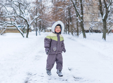 Portrait of a happy little boy playing with a snow outdoor. Winter day. Happy family. Positive human emotions, feelings, joy. Active winter game.の写真素材