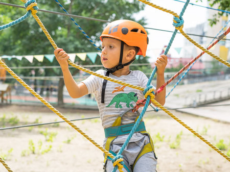 A rock climber tie a knot on a rope. A person is preparing for the ascent. The child learns to tie a knot. Checking the insurance for climbing. Sport climbing in the park.の写真素材