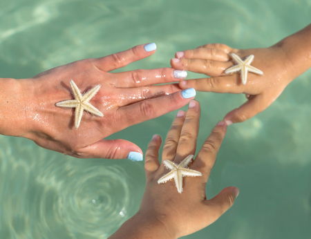 Young Mother and two sons watching starfish. Positive human emotions, feelings, joy. Funny cute child making vacations and enjoying summer. Happy family.の写真素材