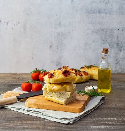 Homemade art focaccia pieces with olive oil, tomatoes, salt, and rosemary. Vertical orientation, copy spaceの写真素材