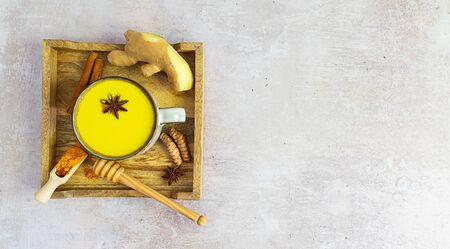 wooden tray with golden ayurveda milk and ingredients: turmeric, cinnamon, honey, and ginger with copy space, top view. Immune boosting remedy, detox and alternative medicine.の写真素材
