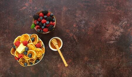 Tiny cereal pancakes, small trendy food with butter, berries, and honeyの写真素材