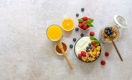 Healthy breakfast concept. Bowl of homemade granola muesli with yogurt, fresh raspberries, blueberries and honey. Top view, copy spaceの写真素材