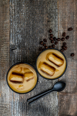 Iced cold coffee latte, vertical orientation. Coffeeish cocktail drink with frozen ice cubes, milk,...