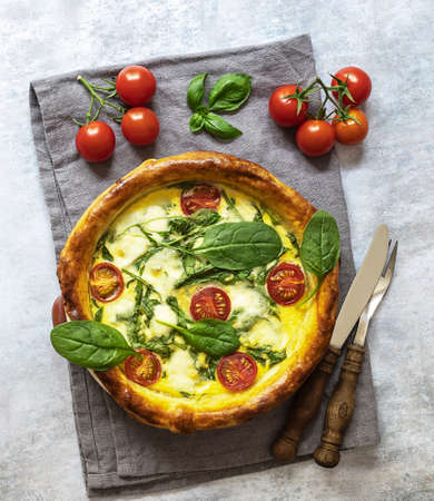 Vegetarian quiche with spinach, feta, and mozzarella cheese, and tomatoes cherry. Top view, rustic cutleryの写真素材