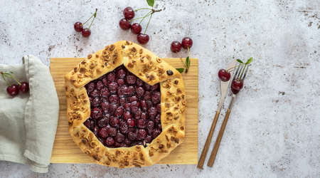 Top view of sour cherry open tart or galette with cutlery and fresh berries. Copy space for recipe or text.の写真素材
