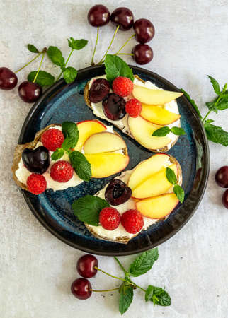 Delicious french toast with fresh fruits, berries, and honey. Tasty breakfast scene or dessert with bread, raspberries, cherries, peach, and ricotta. vertical orientationの写真素材