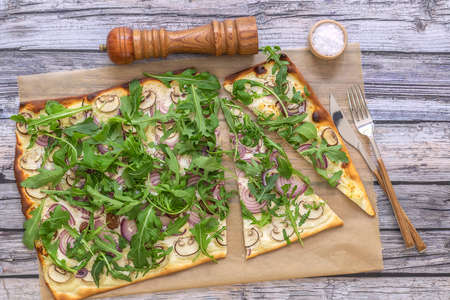 Freshly baked flammkuchen - Traditional German pizza or french Tarte flambee in a vegetarian recipe with mushrooms, cream cheese, onion, and arugula.の写真素材
