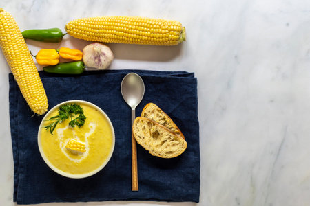 Vegetarian cuisine. Traditional autumn spicy corn soup. Served with corn cobs, greens, cream. top...
