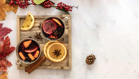 Autumn hot mulled wine in glasses with spices and citrus fruit. top view, decorations on marble tableの写真素材