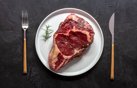 Raw beef rib eye steak. Organic farm meat. Black background.