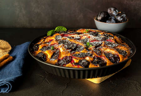 Homemade plum pie with cinnamon. Fruit tart on black table. Autumn harvest timeの写真素材