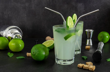 Refreshing alcoholic mint cocktail mojito with rum and lime, cold drink with barmen accessories