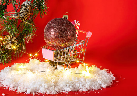 Christmas tree ball in shopping cart with holiday decorations. Postcard with copy space