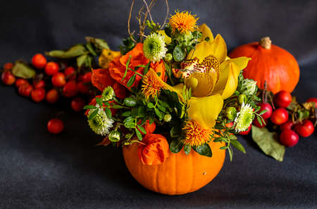 Autumn ikebana from pumpkin, flowers, and decor. Fall colors, still life concept.の写真素材
