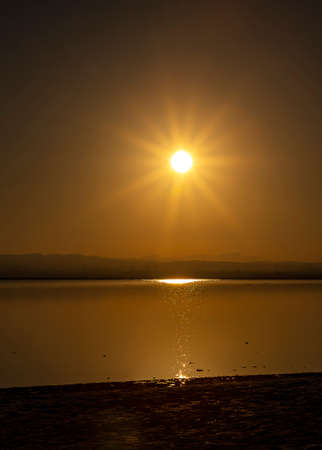 Sunset in calm water with gold reflections, twilight time. Pink salt lake in Spain.の写真素材