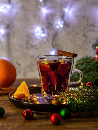 Glass with hot mulled wine and Christmas holiday decorations. Vertical orientation