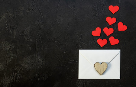 Valentine's day romantic concept. Red wooden hearts and envelop on black background. Top view, flat...