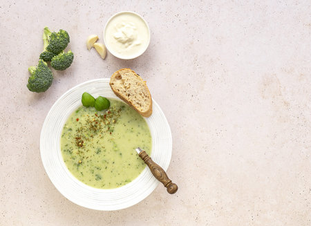 Broccoli cream soup served with cream and fresh bread on light concrete background. Healthy vegetarian food concept. Top view, copy spaceの写真素材