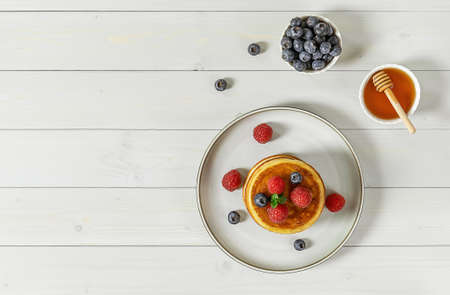 Tasty american pancakes with raspberries, blueberries, and honey. Breakfast concept with copy space.の写真素材