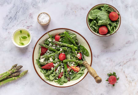 A healthy and delicious salad made from fresh strawberries, green asparagus, feta cheese with vegetable leaves. Vegetarian seasonal food. Detox diet meal.の写真素材